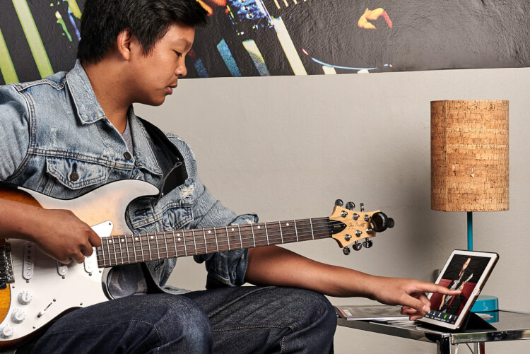 boy student using iPad for online video music lesson