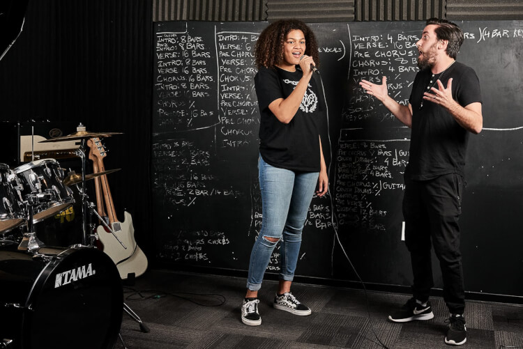 Instructor teaching advanced singing lessons to a teenager