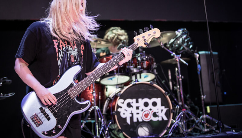 School of Rock student playing the bass guitar on stage