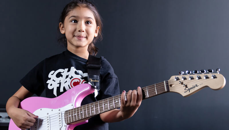 Young girl holding a pink guitar